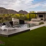 Custom backyard design with raised seating areas, pool and artificial turf.
