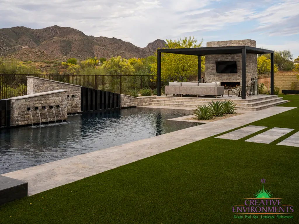Custom backyard design with custom water feature into pool, artificial turf and natural stone decking.