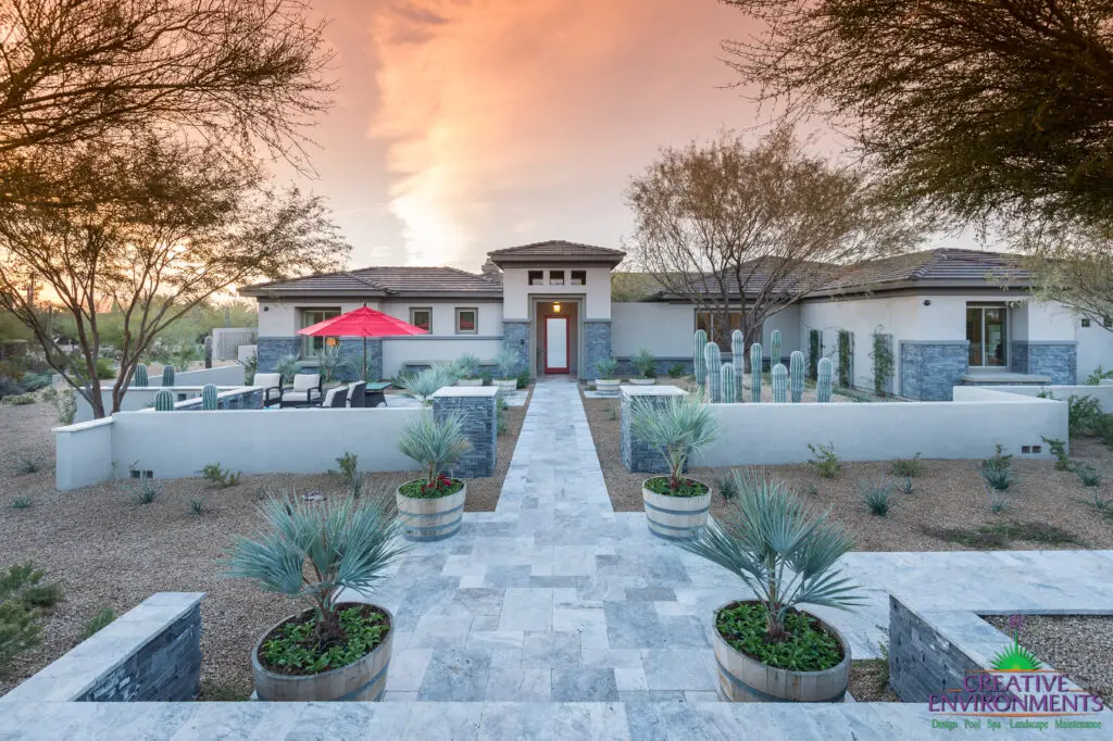 Custom front yard design with natural stone tile pathways, cacti and palm trees.