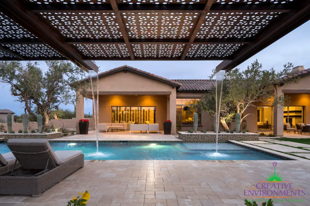 Custom backyard design with cantilevered shade structure with attached metal scupper water feature into pool.