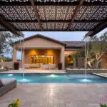 Custom backyard design with cantilevered shade structure with attached metal scupper water feature into pool.