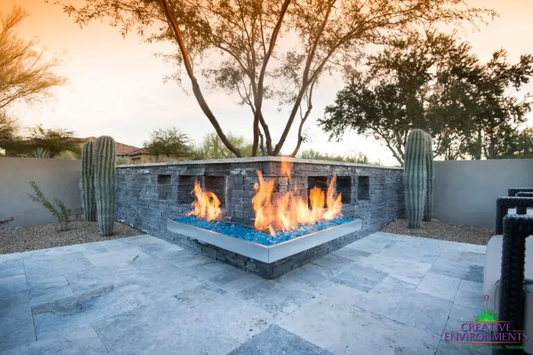 Custom backyard design with angled fireplace, cacti and travertine tiles.