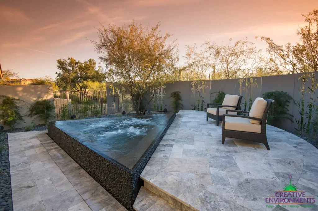 Custom backyard design with triangular spa, raised seating area and privacy wall.