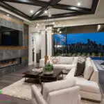 Custom seamless indoor/outdoor living experience with metal fencing, chandelier and metal scupper water feature into pool.