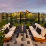 Custom backyard design with floating fire table, metal fencing and outdoor seating area.