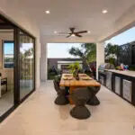 Custom backyard design with recessed lighting, metal statement piece and outdoor kitchen with dining area.