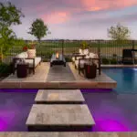 Custom backyard design with Jesus steps, floating fire table and metal scupper water feature into pool.