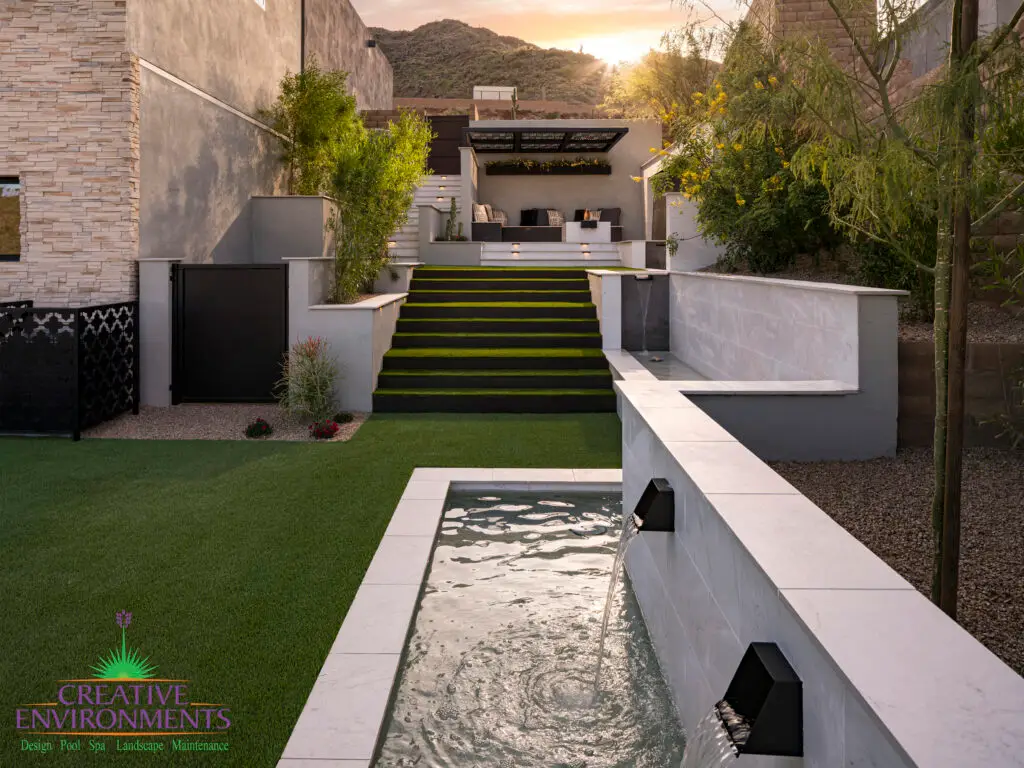 Custom backyard design with natural stone water feature and step lighting