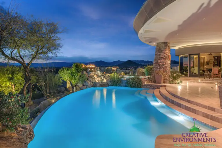 Backyard design with curved pool and up lighting.