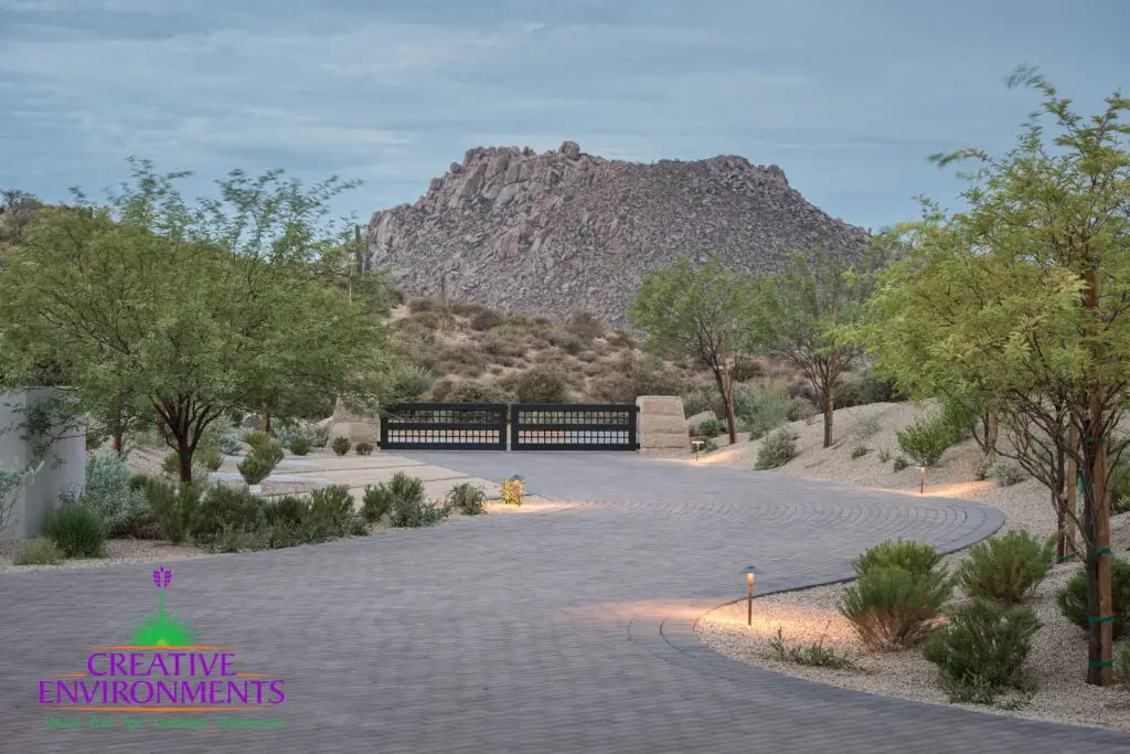 Custom paver driveway with desert plants and metal entry gate.