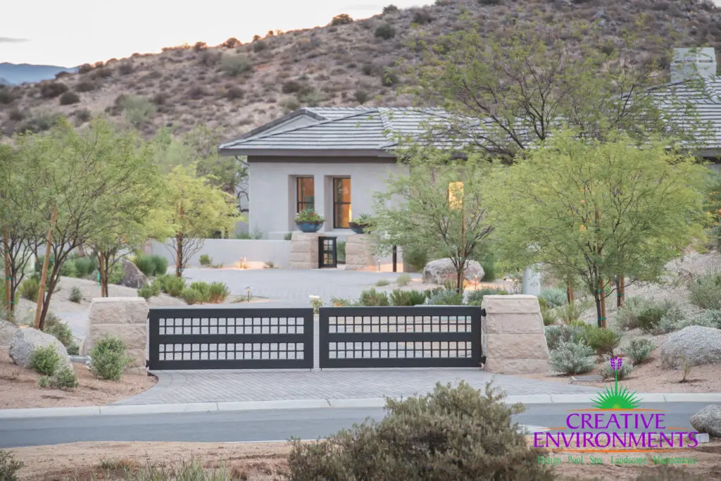 Custom metal entry gate with roundabout driveway and desert landscaping.
