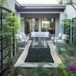 Custom metal trellis with Ivy, black pebble stone water feature and multiple seating areas.