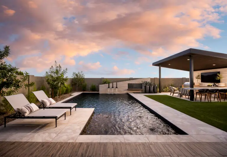 Custom backyard design with multiple seating areas and water feature into pool.