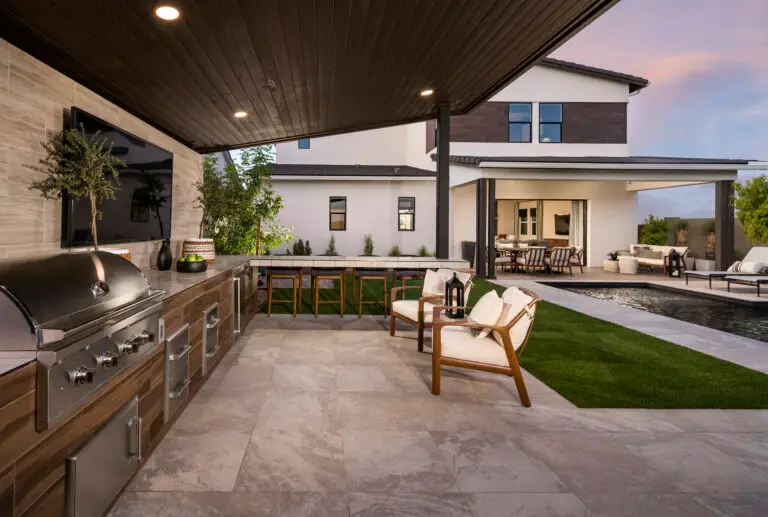 Custom backyard design with outdoor kitchen and angled shade structure.