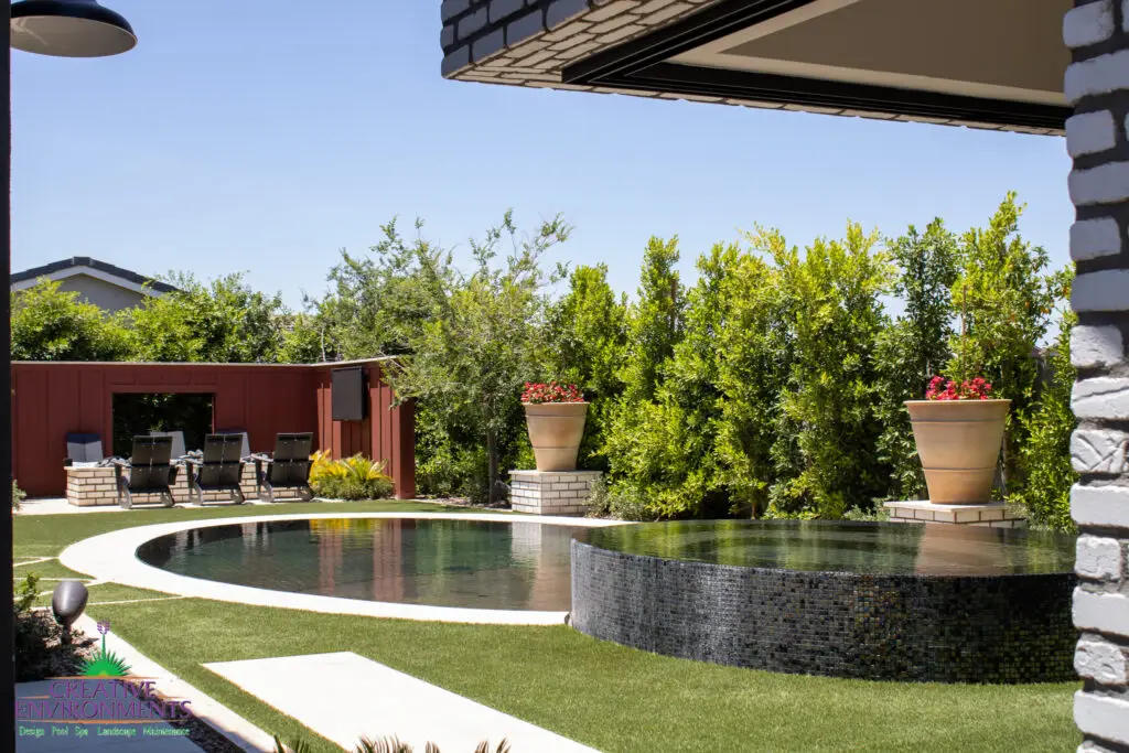 Custom backyard design with circular raised spa, circular pool and privacy hedges.
