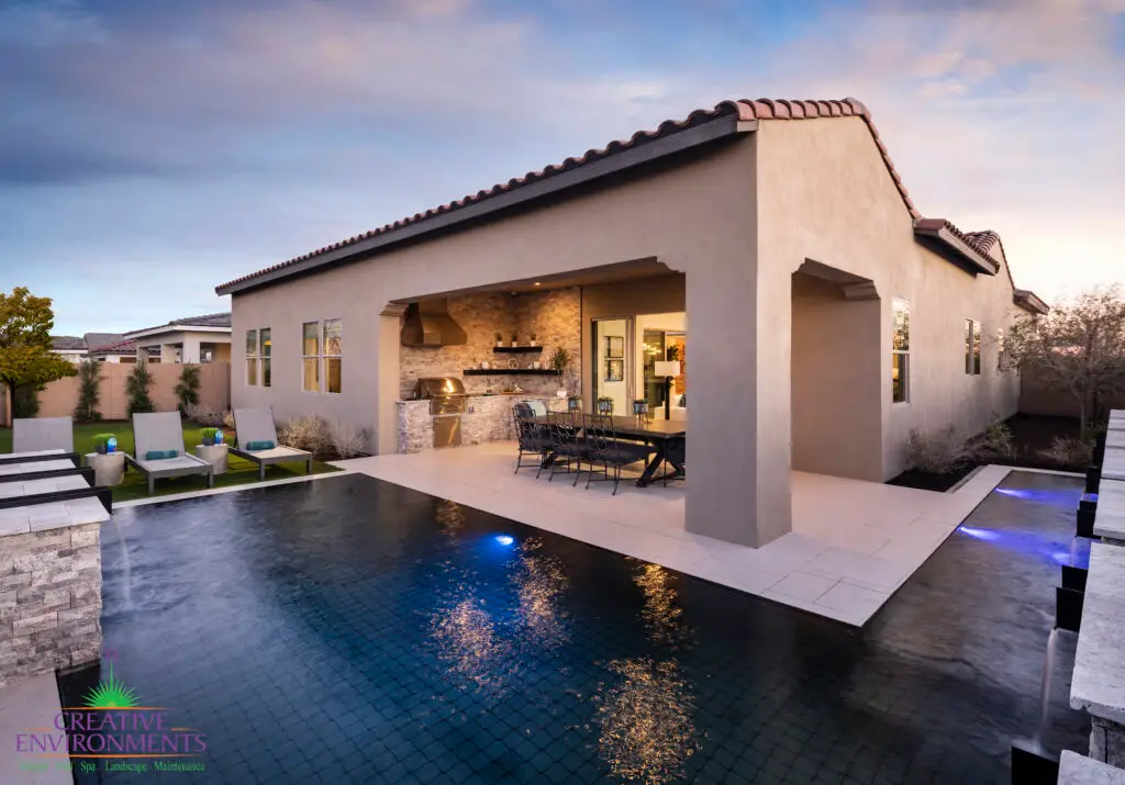 Custom backyard design with zero edge pool with blue pool lighting and multiple seating areas.