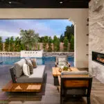 Custom backyard design with marble fireplace, metal water scupper feature and privacy hedges.