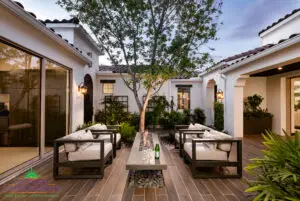 Custom entryway courtyard with large tree, multiple large metal planters and floating fire table.