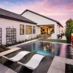 Custom backyard design with living wall, zero-edge pool with baja step and metal trellis.