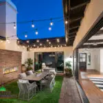 Custom backyard design with string lights, fireplace and outdoor dining area.