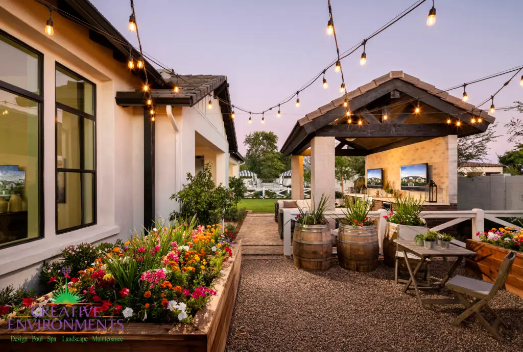 Custom backyard design with multiple outdoor TV's, string lights and annuals.