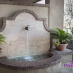 Custom backyard design with planters, faucet water feature and Spanish design style.