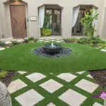 Custom backyard design with artificial turf pattern, black water feature and black beach pebbles.