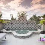 Custom backyard design with deco-tile water feature, Spanish design style and outdoor seating area.