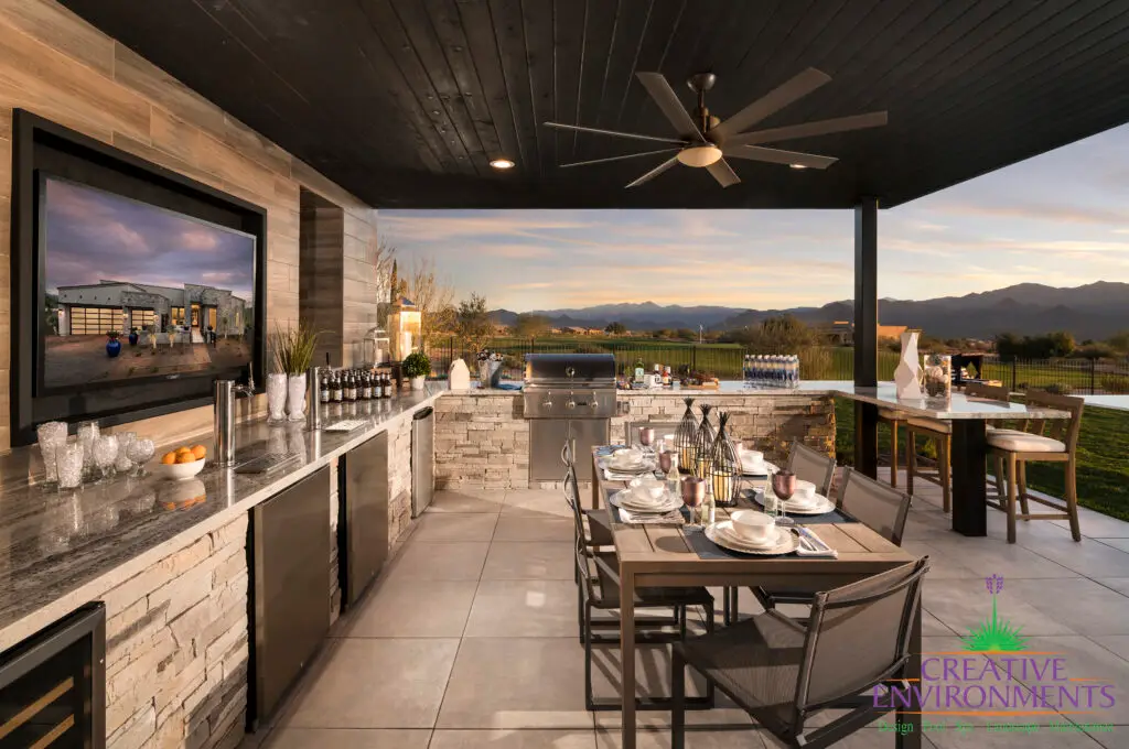 Custom backyard design with outdoor kitchen, multiple seating areas and metal fencing.