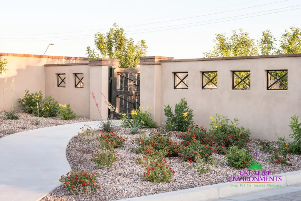 Custom community entrance with metal cutouts, metal gate door and organized planting.