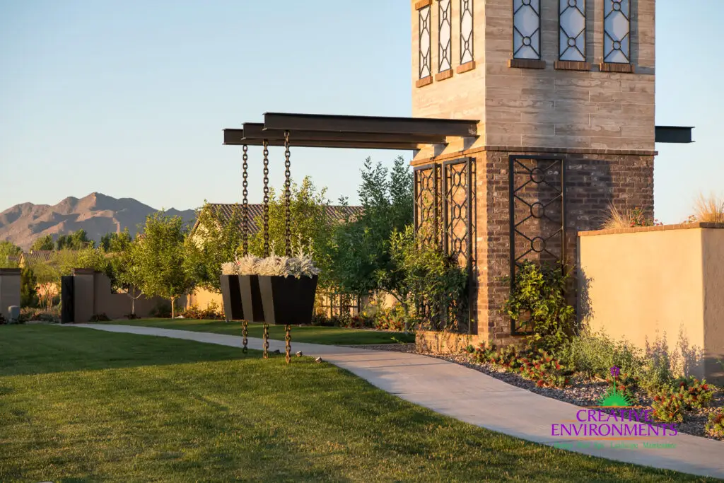Custom community entrance with cantilevered planters, metal trellis and concrete pathway.