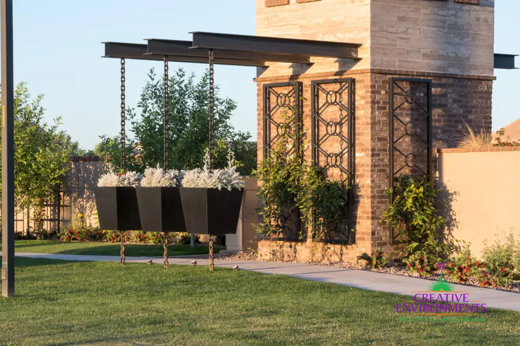 Custom community entrance with cantilevered shade structure, metal trellis and annuals.