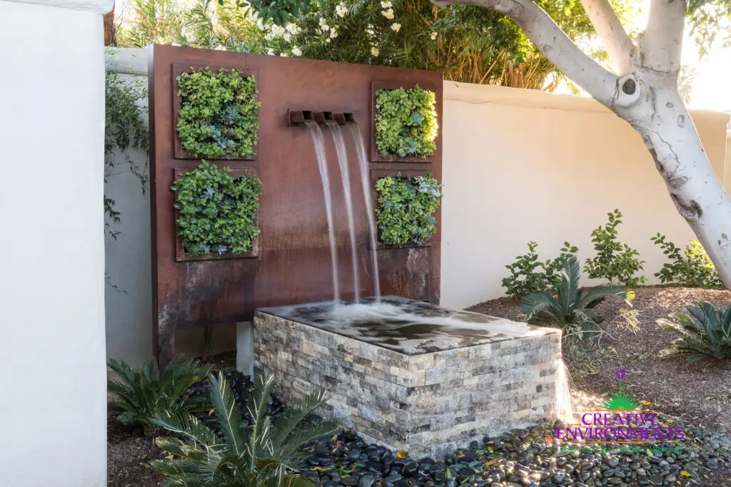 Custom backyard design with succulent living wall, metal scupper water feature and organized planting.