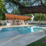 Custom backyard design with angled shade structure, deco-tile pool and multiple seating areas.