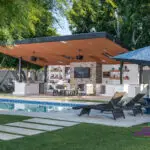 Custom backyard design with real grass, angled shade structure and outdoor entertainment area.