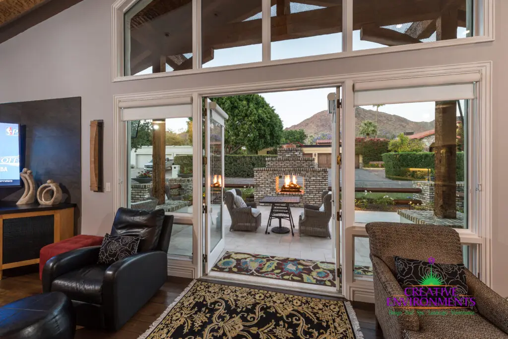 Custom indoor/outdoor design fusion with multiple seating areas, privacy hedges and outdoor fireplace.