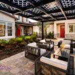 Custom backyard design with fireplace, metal shade structure with patterned roof and organized planting.