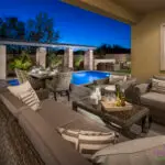 Custom backyard design with multiple seating areas, natural stone outdoor kitchen and blue pool.