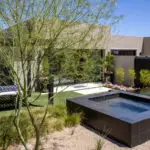 Custom backyard design with raised black spa, real grass and organized planting.
