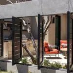 Custom backyard design with metal shutters, outdoor dining area and outdoor BBQ.