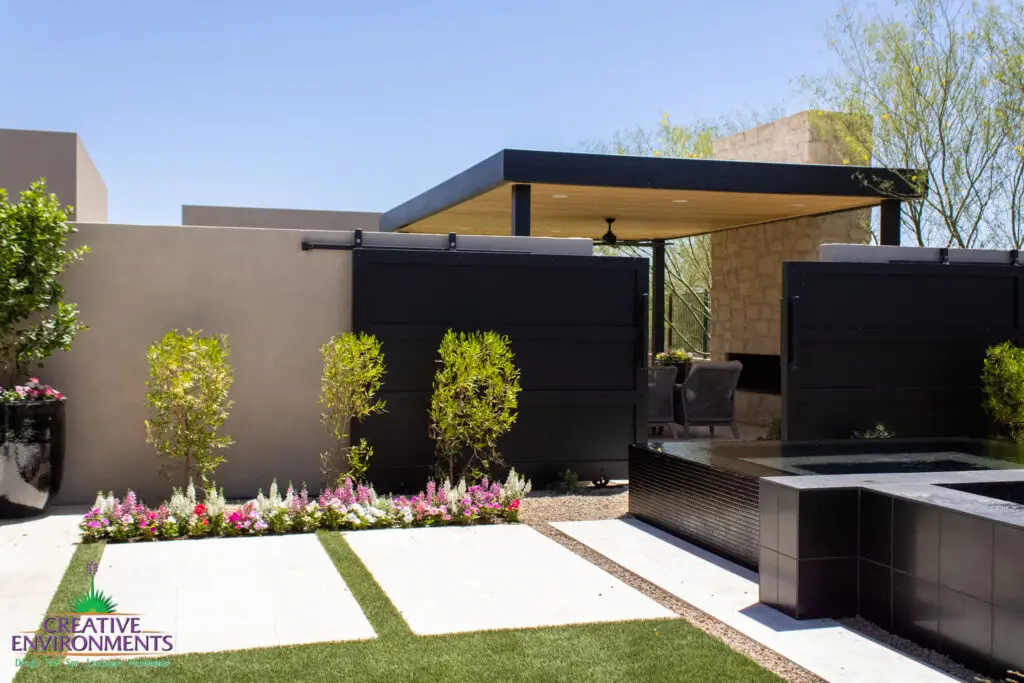 Custom backyard design with black entry gate, raised spa and organized planting.