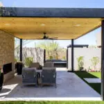 Custom backyard design with metal shade structure, natural stone fireplace and artificial turf.