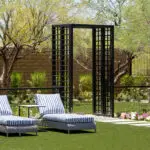 Custom backyard design with organized planting, metal archway and metal fencing.