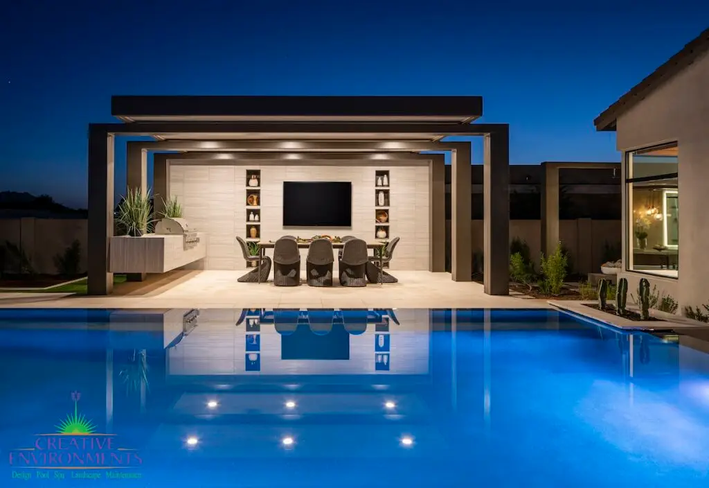 Custom backyard design with pool lighting, desert plants and built-in outdoor shelves.