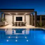 Custom backyard design with pool lighting, desert plants and built-in outdoor shelves.