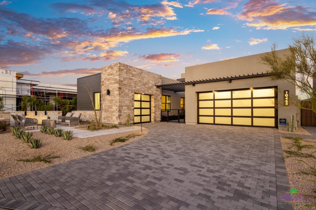 Custom front yard design with outdoor seating area, linear flower planters and brick paver driveway.