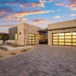 Custom front yard design with outdoor seating area, linear flower planters and brick paver driveway.