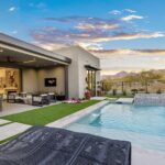 Custom backyard design with metal scupper water feature, blue pool and multiple seating areas.