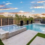 Custom backyard design with blue pool, custom metal dividers and raised spa.