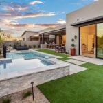 Custom backyard design with artificial grass, raised spa and blue pool.